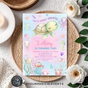 Puede incluir: Una invitación caprichosa con un diseño de temática marina. Presenta una tortuga de dibujos animados, estrellas de mar y otra vida marina. El texto dice "Let's Shell-ebrate!" y anuncia una fiesta de cumpleaños para Leilany, que cumple dos años.