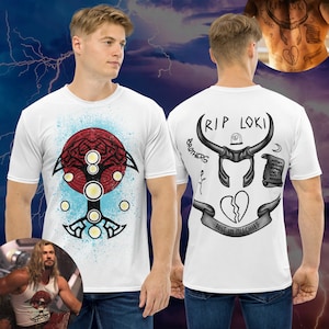 Könnte beinhalten: Weißes T-Shirt mit einem schwarz-weißen Baumdesign auf der Vorderseite und einem schwarz-weißen "RIP Loki"-Design auf der Rückseite. Das Design auf der Rückseite enthält ein gebrochenes Herz, einen gehörnten Helm, einen Grabstein und eine Schriftrolle.