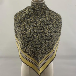 May include: A square scarf with a repeating yellow rose pattern on a black background. The scarf has a yellow border with white and brown stripes. The scarf is displayed on a mannequin.