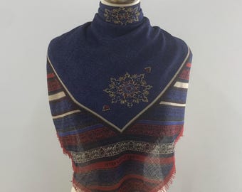 May include: A blue and red patterned scarf with a fringe border. The scarf has a geometric design with a central floral motif.