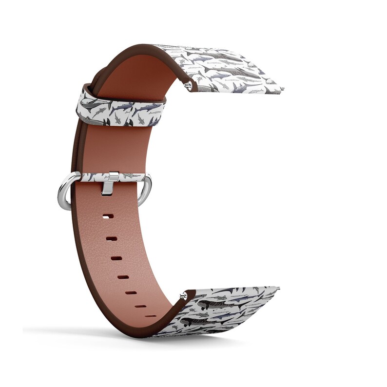 May include: A white leather watch strap with a brown leather band and a pattern of sharks. The strap has a silver buckle and a silver loop.