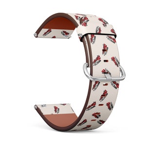 May include: A white leather watch band with a red and white fire truck pattern. The band has a brown leather lining and a silver buckle.