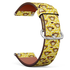 May include: A yellow watch band with a repeating pattern of smiling brown monkeys and bananas. The band has a brown leather backing and a silver buckle. The watch band is designed to attach to a watch face.