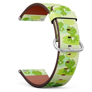 May include: A watch strap with a playful frog pattern. The strap displays a light green backdrop with repeated images of smiling frogs on lily pads. It has a brown leather backing and a silver buckle. The strap is approximately 1.9 cm wide.