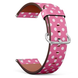 May include: Pink watch strap featuring white polka dots. The strap has a brown underside and a silver buckle. The watch strap is made of a smooth material and is designed to attach to a watch face.