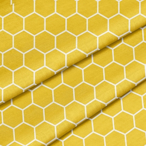 Peut inclure: Tissu jaune avec un motif en nid d'abeille blanc. Le tissu est plié en deux, créant un effet de superposition.