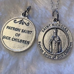 May include: Silver chain necklace with two round silver medallions. The larger medallion features a depiction of Saint Nicholas and the text "Saint Nicholas Patron Saint of Sick Children". The smaller medallion features the text "Patron Saint of Sick Children".