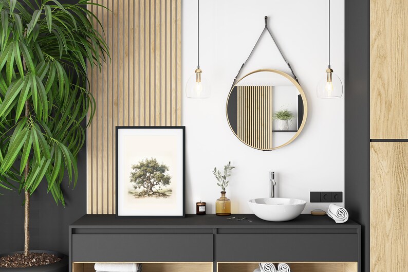 May include: A modern bathroom interior featuring a framed tree art print, a round mirror with a gold frame, and a white sink. The decor includes a large green plant, pendant lights, and wooden accents, creating a serene and stylish space.
