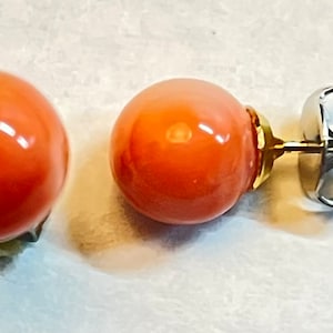 May include: A pair of coral stud earrings with silver posts and butterfly backs.
