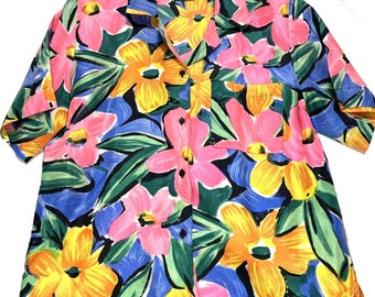 Könnte beinhalten: Ein kurzärmeliges Hemd mit Knöpfen und einem farbenfrohen Blumendruck. Das Hemd hat ein großflächiges Design mit rosa, gelben und blauen Blumen auf dunkelblauem Hintergrund.