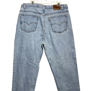 May include: A pair of light blue denim jeans with a brown leather patch on the back waistband. The jeans have a classic five-pocket style.