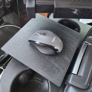 May include: A gray Logitech wireless mouse on a black mousepad. The mousepad is on a black surface.
