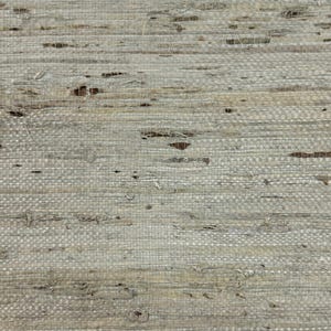 Puede incluir: Primer plano de un textil tejido con un aspecto natural y texturizado. El material es principalmente gris claro con sutiles variaciones de tono y peque&ntilde;as manchas marrones oscuras. El tejido es visible, creando un patr&oacute;n similar a una cuadr&iacute;cula.