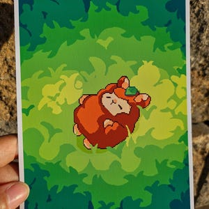 May include: A pixelated illustration of a brown and orange creature with a green gem on its head, lying on a green and yellow background.