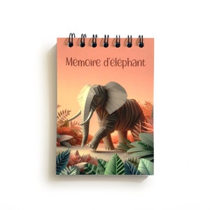 Peut inclure: Un carnet à spirales avec une illustration colorée d'un éléphant dans un décor de jungle. La couverture porte l'inscription "Mémoire d'éléphant".