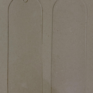 May include: Two clear acrylic bookmarks with rounded tops and a small hole at the top of one. The bookmarks are rectangular with a slightly arched top. They are displayed on a neutral, textured background.