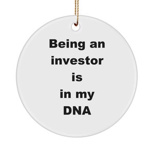 Op de afbeelding: Witte keramische ornament met de tekst "Een belegger zijn zit in mijn DNA".