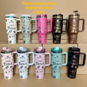 May include: A collection of Stanley tumblers in various colors, featuring a Stitch character design. The tumblers have handles and lids, with the Stitch logo and floral accents. The text "Please check other listing for other colour" is visible.