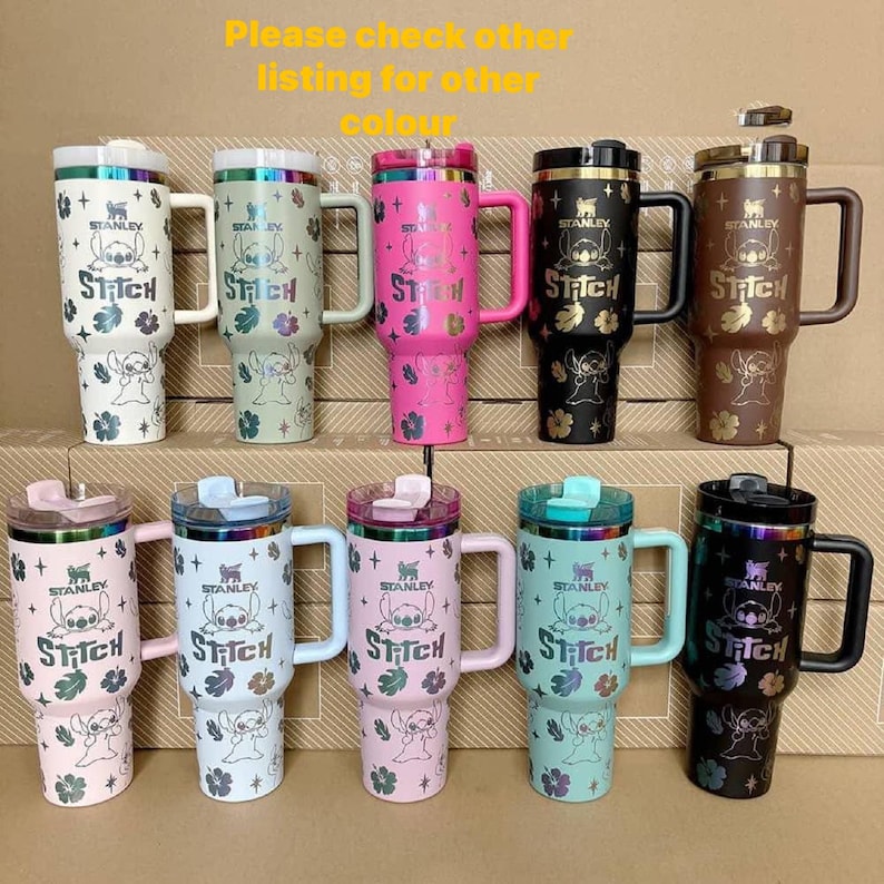 May include: A collection of Stanley tumblers in various colors, featuring a Stitch character design. The tumblers have handles and lids, with the Stitch logo and floral accents. The text "Please check other listing for other colour" is visible.