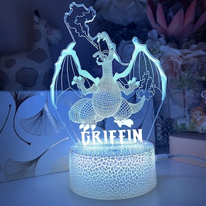 May include: A white night light with a 3D dragon design and the name "GRIFFIN" printed on the base. The light is on and illuminating the dragon.