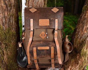 May include: A brown leather and canvas backpack with adjustable straps, a front pocket, and two side pouches. The backpack has a worn, vintage look and is perfect for hiking or camping.
