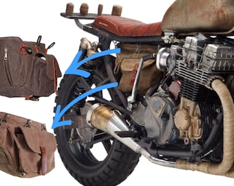 May include: A brown leather motorcycle saddlebag with a zippered pocket and a buckle closure. The bag is attached to a motorcycle with a strap.