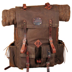 May include: A brown canvas backpack with leather straps and buckles. The backpack has a large main compartment and two smaller pockets on the front. The backpack is made of durable materials and is perfect for carrying all of your essentials.