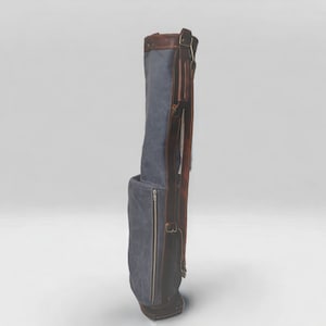 May include: A blue canvas golf bag with brown leather accents and straps. The bag has a zippered pocket on the side.