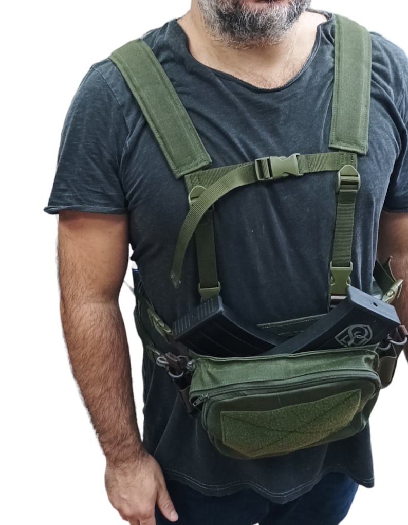 May include: A green tactical chest rig with two magazine pouches and a large front pouch. The rig has adjustable straps and a buckle closure.
