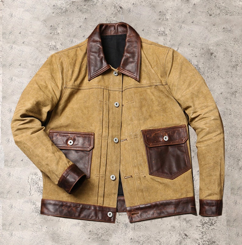 May include: A brown and tan jacket with a brown leather collar and pockets. The jacket has a button closure and a brown leather trim around the bottom.