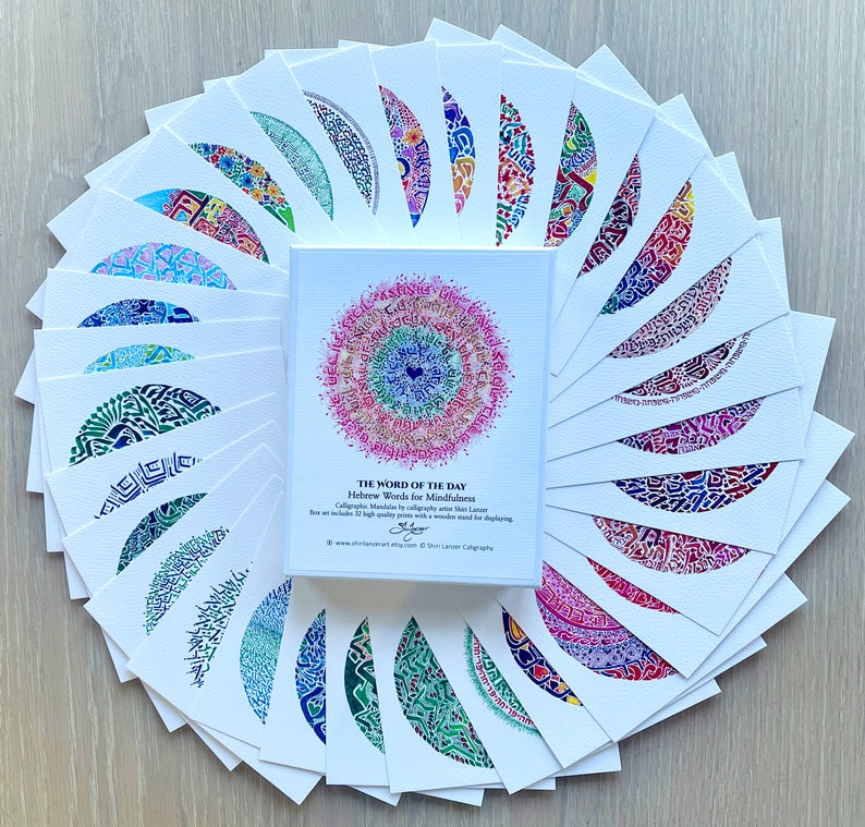 May include: A set of 12 cards featuring Hebrew words for mindfulness, each word is calligraphed in a colorful mandala design. The cards are arranged in a fan shape, with the title card in the center. The title card reads "The Word of the Day: Hebrew Words for Mindfulness".