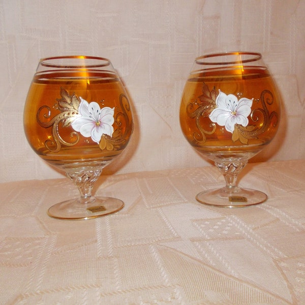 paire de verres à cognac en cristal de Bohême  or irisé ornés d'une fleur blanche et filets d'or en haut et en bas  sur pied torsadés