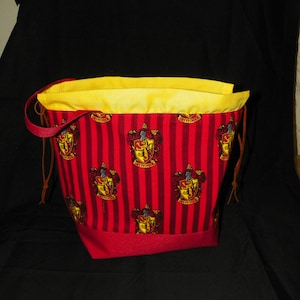 Op de afbeelding: Rode en gele trekkoordtas met een Gryffindor-huiswapenpatroon. De tas heeft een gele voering en rode bies.