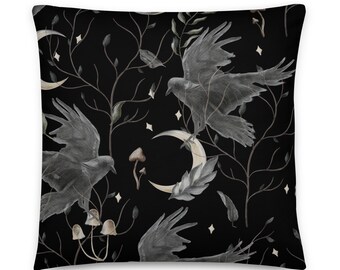 May include: A black and white cushion with a repeating pattern of crows, crescent moons, mushrooms, and branches. The pattern is on a black background.