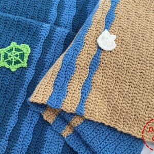 May include: A crocheted blanket with blue and brown stripes. The blanket has a green turtle applique and white flower appliques. The text "pattern only" is visible in the lower right corner of the image.