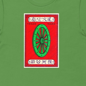 May include: Green t-shirt with a red and white matchbox label featuring a green wheel with the text "Trade Mark" and "酒來大通" in Japanese characters.