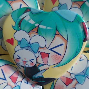 May include: A collection of heart-shaped buttons featuring a cartoon character with teal hair and a bunny. The buttons have a yellow background with red heart accents. The character is smiling and holding a bunny.