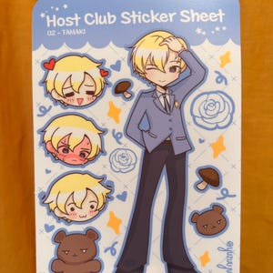 K&ouml;nnte beinhalten: Ein Stickerbogen mit Illustrationen aus der Host Club-Serie. Der Bogen enth&auml;lt eine Ganzk&ouml;rperillustration eines Charakters in einem blauen Anzug sowie kleinere Aufkleber des Gesichts des Charakters und einen braunen B&auml;ren. Der Text "Host Club Sticker Sheet" ist sichtbar.