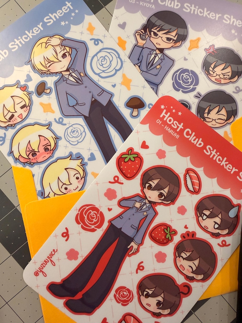 K&ouml;nnte beinhalten: Mehrere Stickerb&ouml;gen mit Illustrationen von Charakteren im Anime-Stil in Anz&uuml;gen. Die B&ouml;gen haben ein hellblaues und wei&szlig;es Farbschema mit dem Text "Host Club Sticker Sheet". Die Aufkleber enthalten Bilder von Erdbeeren, Rosen und anderen dekorativen Elementen.