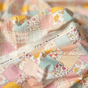 May include: A patchwork fabric with a variety of floral patterns in shades of pink, yellow, blue, and white. The fabric is made of 100% cotton and has a soft, textured feel.