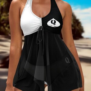 May include: Black and white halter swimsuit with a queen of hearts design. The swimsuit has a gathered detail at the waist and a ruffled hem.