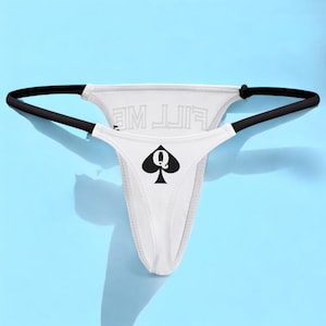 Op de afbeelding: Witte string onderbroek met zwarte bies en een zwart schoppen vrouw symbool met de tekst "FILL ME" gedrukt op de achterkant.