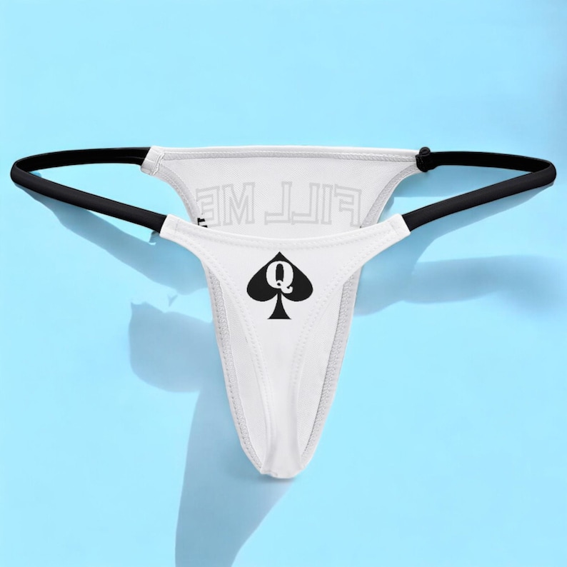 Op de afbeelding: Witte string onderbroek met zwarte bies en een zwart schoppen vrouw symbool met de tekst "FILL ME" gedrukt op de achterkant.
