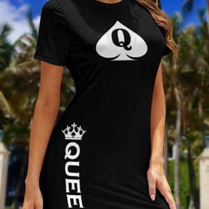 May include: A black short-sleeved dress featuring a white spade symbol with the letter Q inside on the chest. The word QUEEN is printed vertically in white along the lower right side, topped with a small white crown graphic above the text.