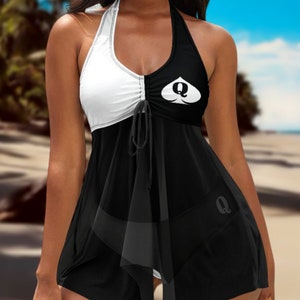May include: Black and white halter swimsuit with a queen of spades design. The swimsuit has a ruffled skirt and a tie at the bust.