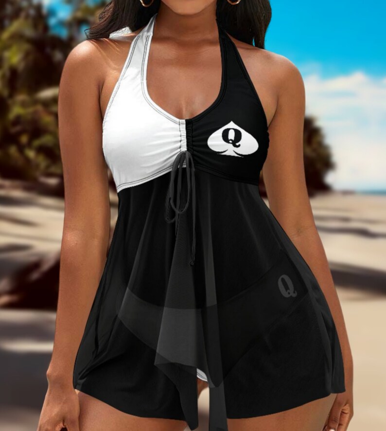 May include: Black and white halter swimsuit with a queen of spades design. The swimsuit has a ruffled skirt and a tie at the bust.