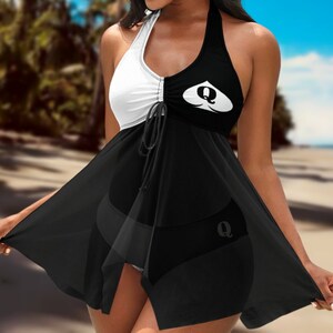 May include: Black and white swimsuit cover-up with a queen of hearts design. The cover-up has a halter neck and a flowing skirt.