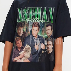 May include: Black t-shirt with a collage of images and the name "Nathan Fillion" in green text. The shirt has a vintage, distressed design, with multiple images of the actor. The text "Prospect Shop Art" is also visible.