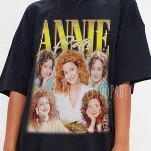 May include: Black oversized t-shirt with a vintage-style graphic of the band "Annie's Dolls". The graphic features five women with curly hair and a gold background.