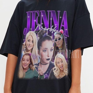 Puede incluir: Camiseta negra de gran tamaño con un estampado gráfico de Jenna Marbles. El gráfico presenta un collage de imágenes de Jenna Marbles con diferentes atuendos y poses. El texto "Jenna Marbles" está impreso en morado y con un contorno blanco.